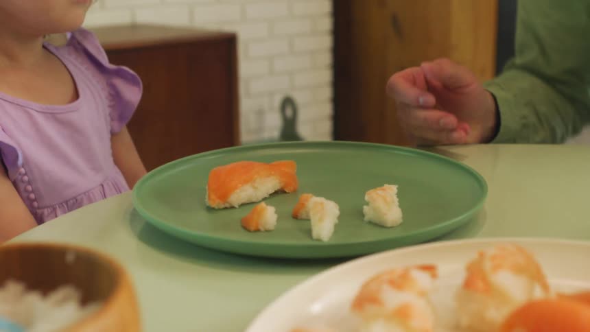 Man sets plates on table and sits near daughter