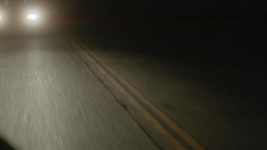 A vehicle with headlights driving on a road