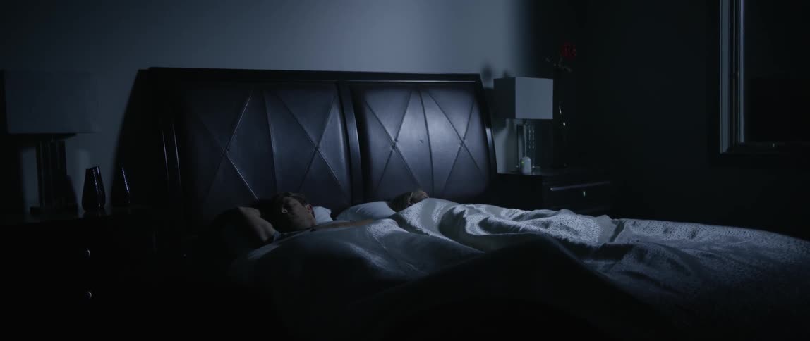 A couple lie asleep in bed during the night