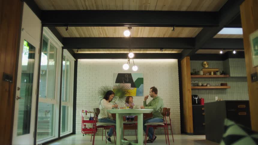A toddler laughs while sitting at the dinner table with her parents