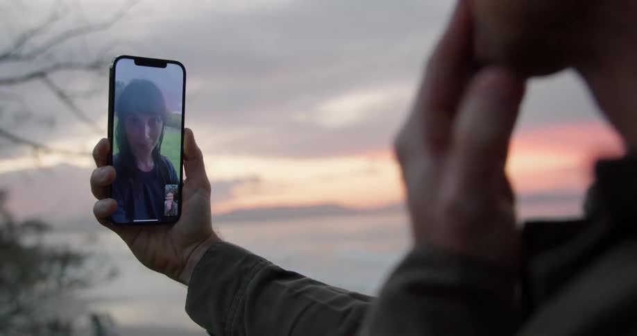 A man and a woman are blowing a kiss to each other during a video call on a cell phone