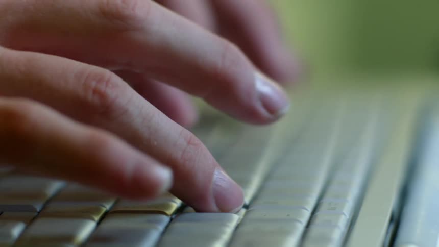 Close view of a womans hands as she types on a laptop while indoors during the day