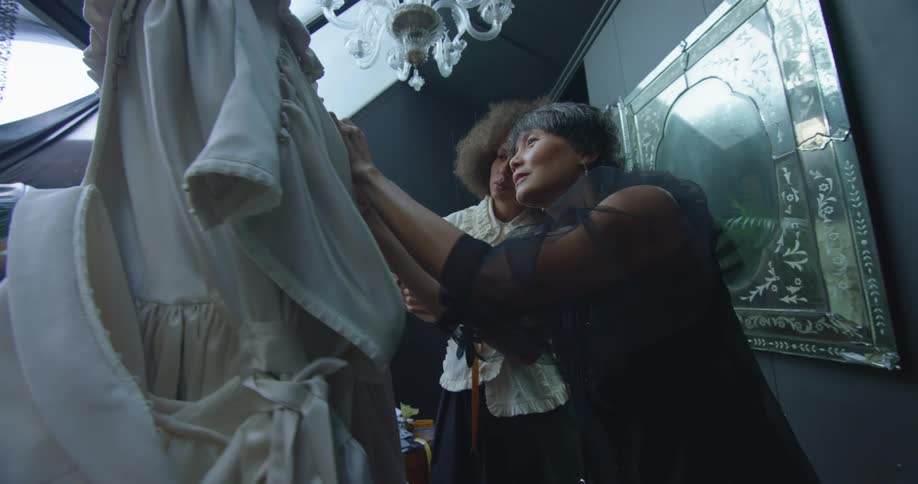 Two women talk and look at clothing together