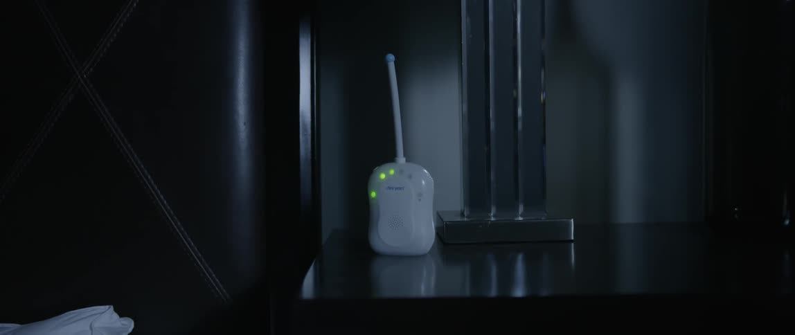 A baby monitor on a table flashes red and green lights