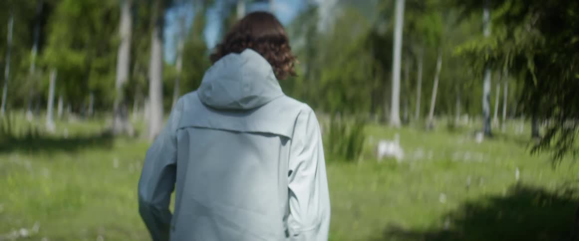 A man is hiking in the grass through the forest
