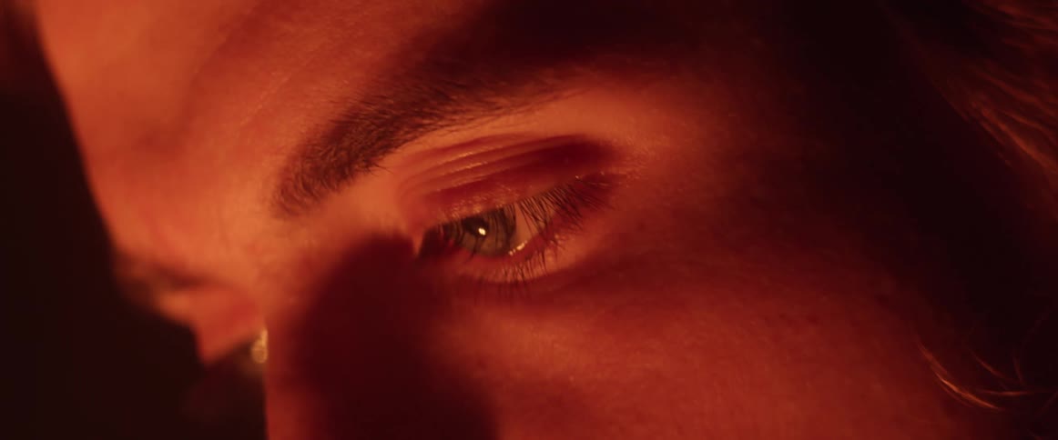A man is looking ahead as red light shines on his face