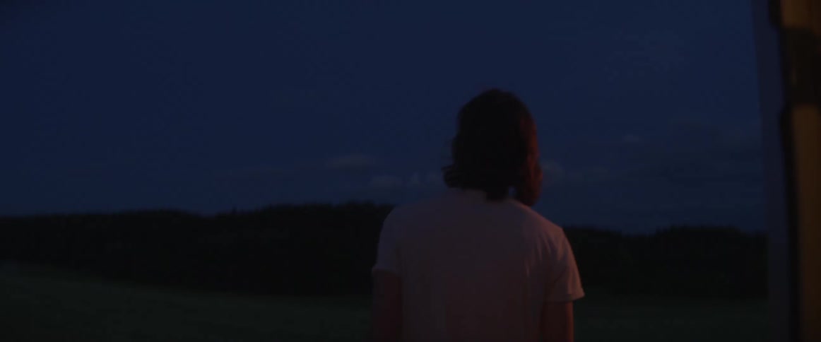 Man walks out of camper and stands looking at horizon at night