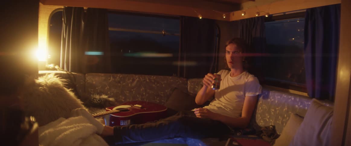 A musician has a drink while sitting on his tour bus