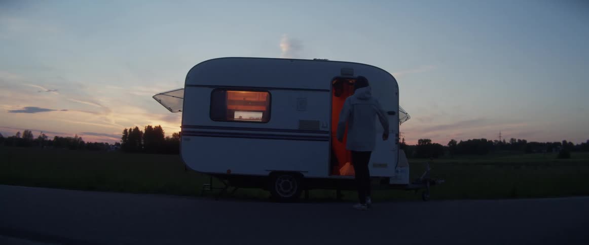 A man walks up to a camper then goes in