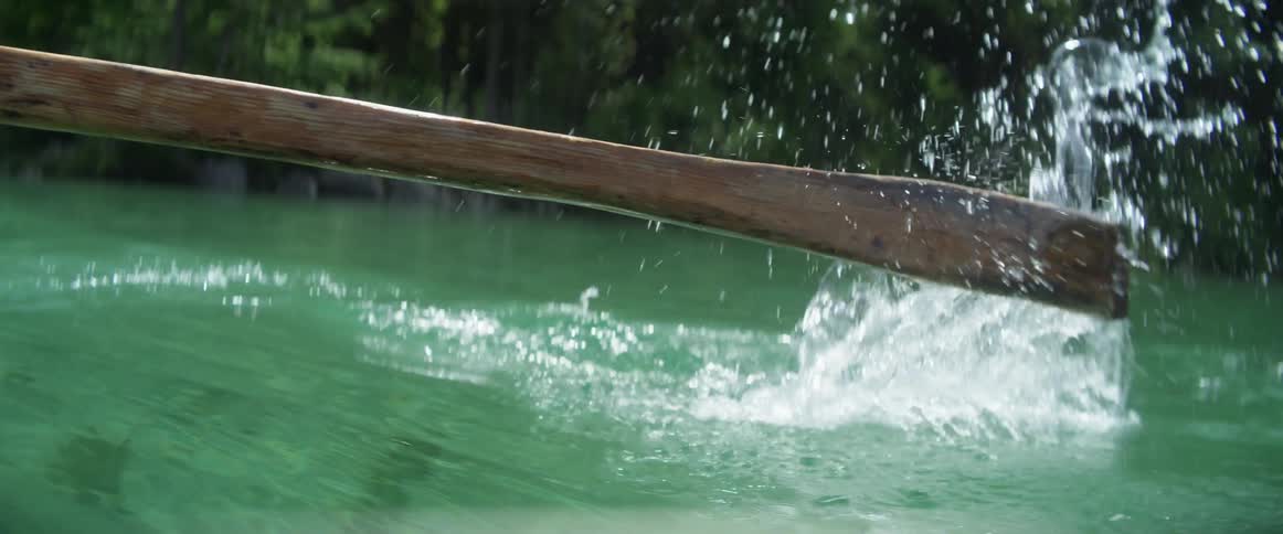 An oar is moving through the water of the river