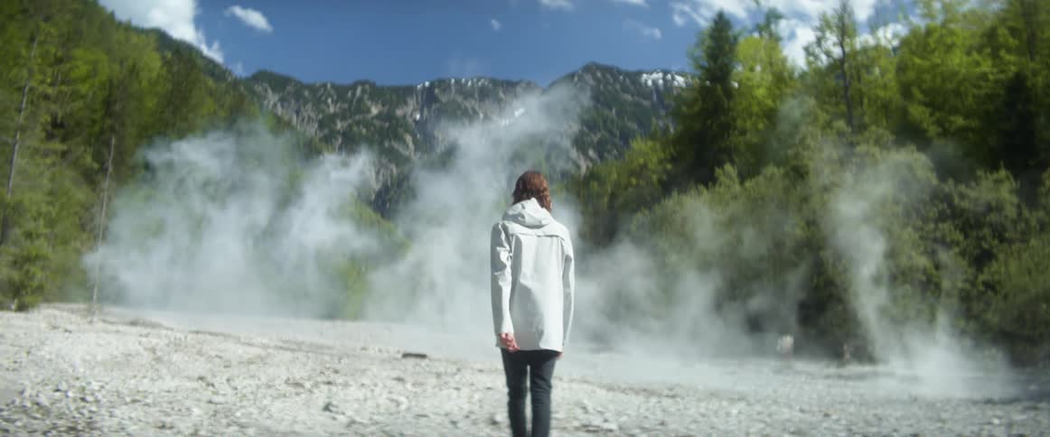 A teenage boy walks towards a forest with smoke billowing out