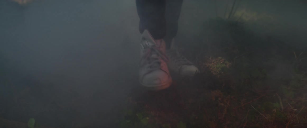 A person is walking through a foggy forest