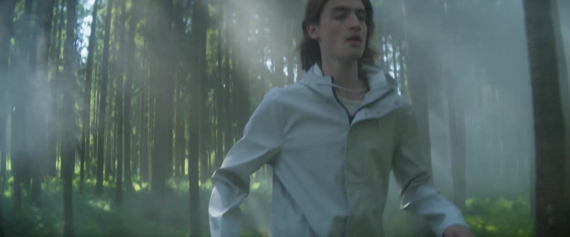 A young man running alone in a misty forest on a summer day