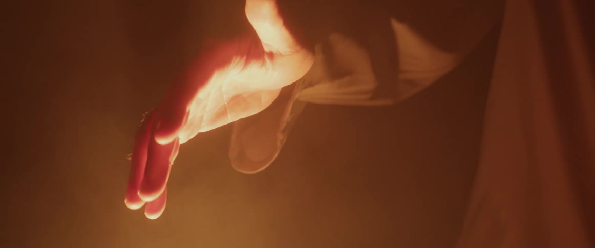 A man moves his hand up and down over a fire