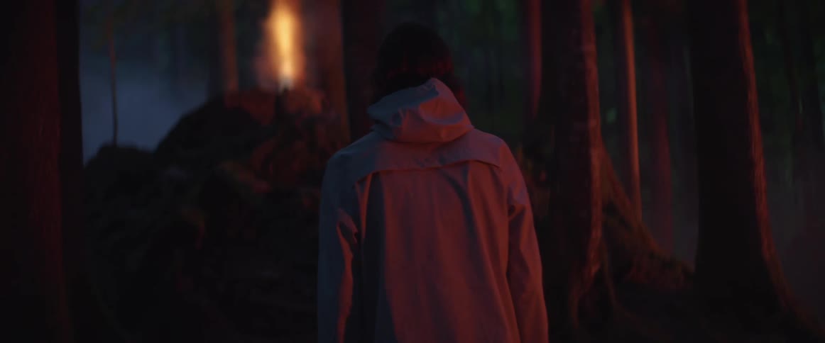 A man is hiking towards a light in the woods