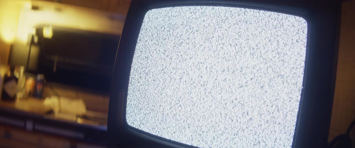 An old television has static on the screen indoors at night