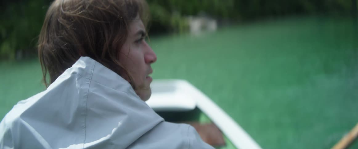 A man looks backward as he rows a boat