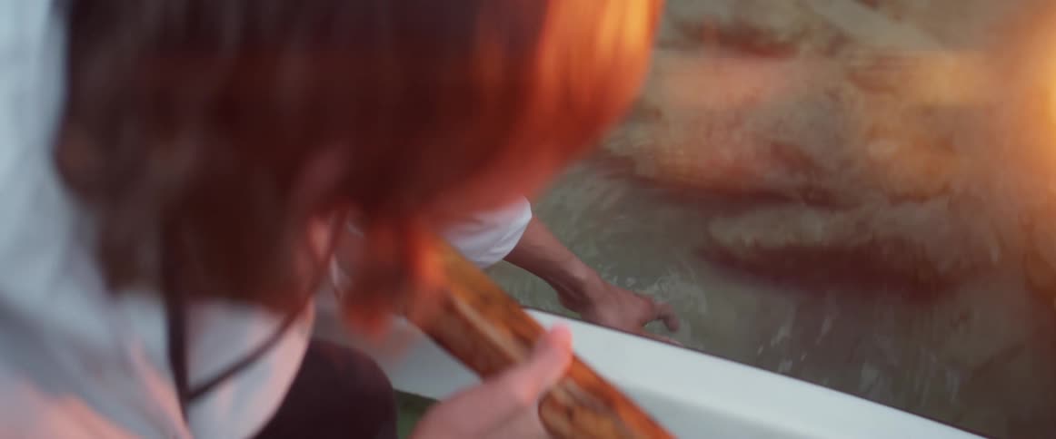 A person in a boat puts their hand in the water