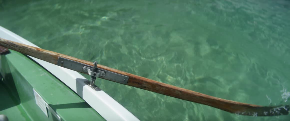 A person rows the oars of a boat on water