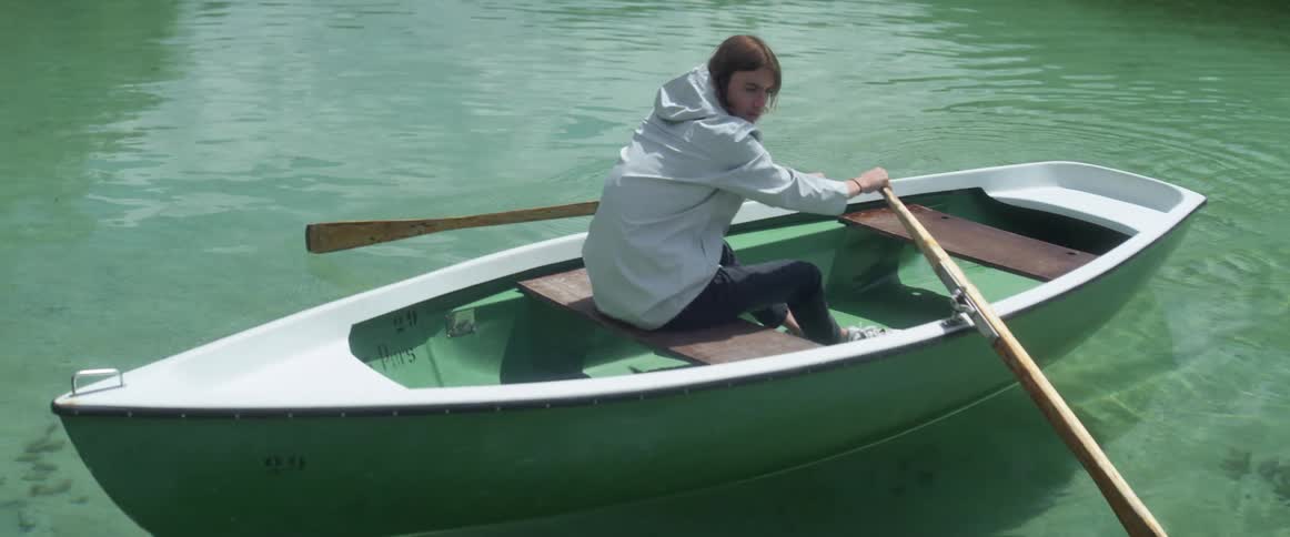 A man rows the oars of a boat and looks behind him
