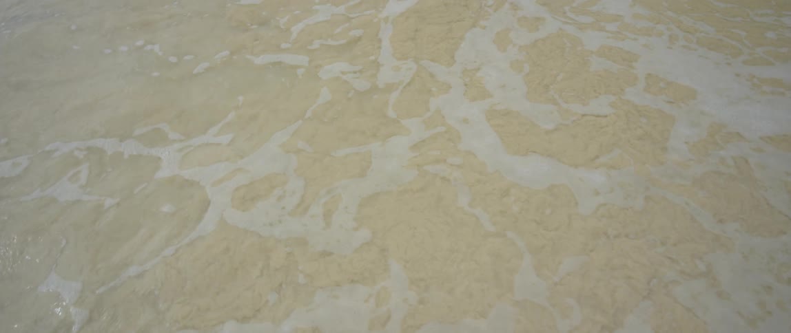 White foam sits on top of shallow churning water