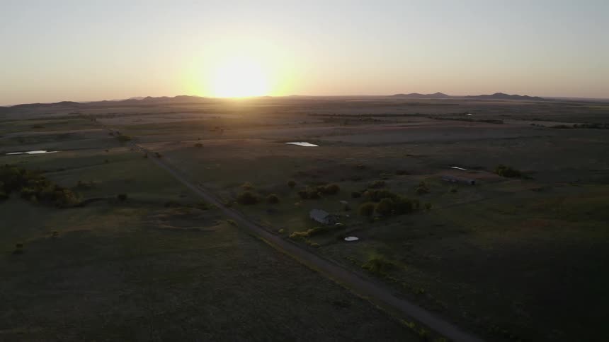 A home sits off a dirt road surrounded by farmland
