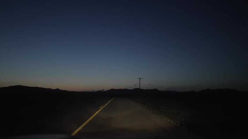 Traveling down a two lane country road with headlights on