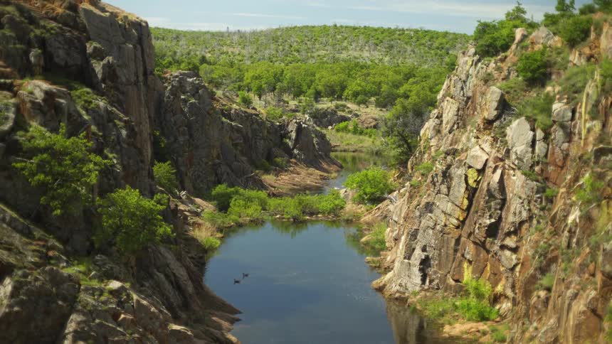 Ducks are floating on a stream between two rock faces