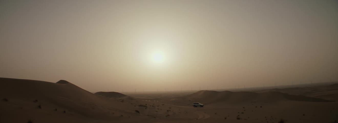 A car driving in a sandy desert on a sunny day