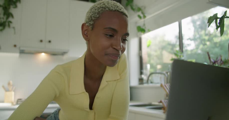 A woman talks on the laptop in her kitchen