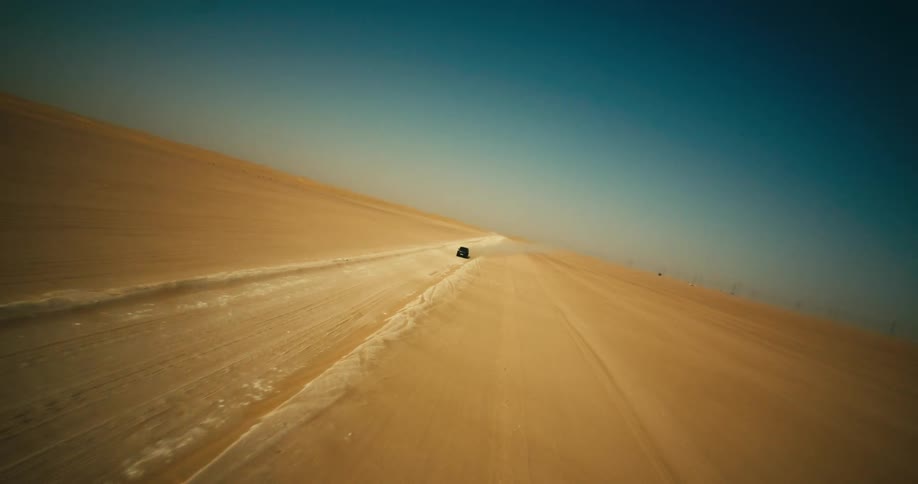 Aerial view of black jeep driving across desert