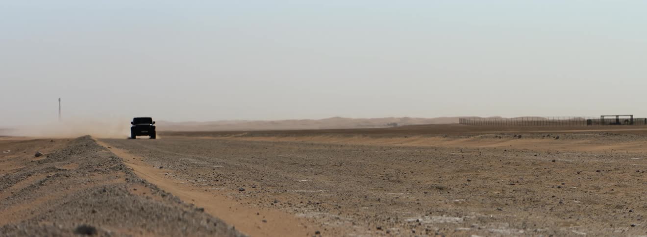 Dust flying in to the air as a truck drives across a soiled field