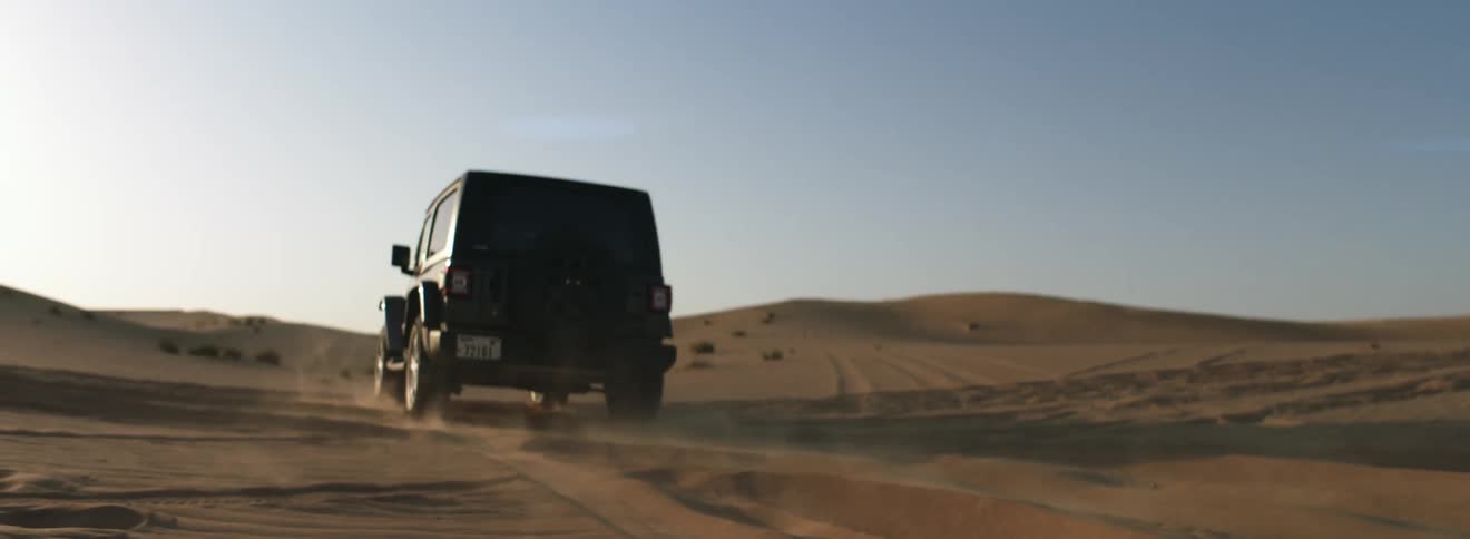 A car driving on sand in a remote desert in the daytime