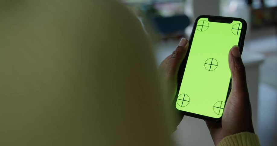 A woman is sitting in a living room while swiping her thumb across and smartphone screen in the daytime
