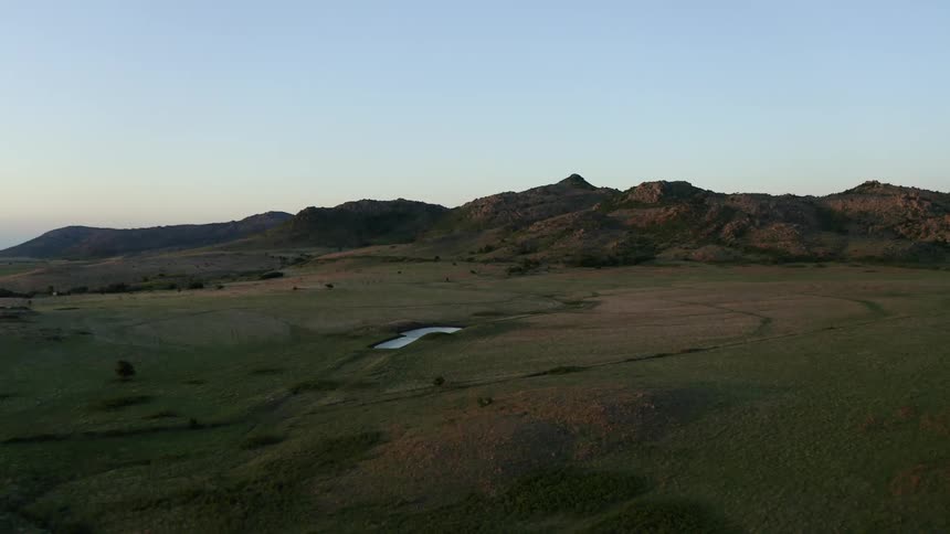A landscape with grass with a mountain range the sky and clouds in the background