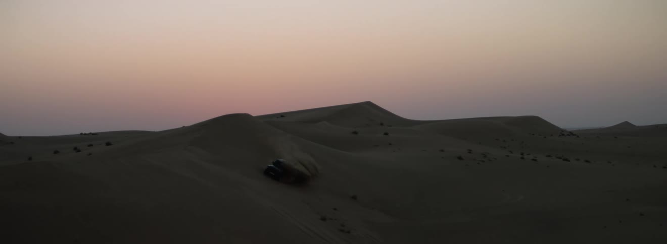 A vehicle slides down the dune in the desert