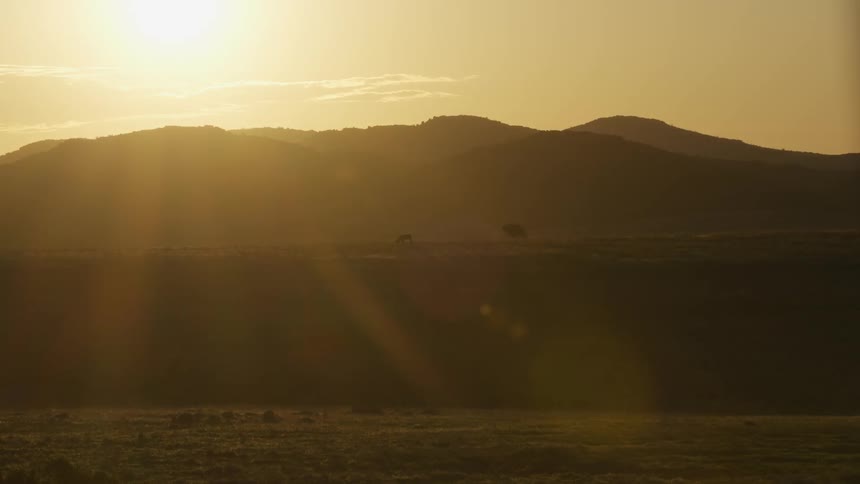 Sunlight shines brightly over a mountain obstructing the view below