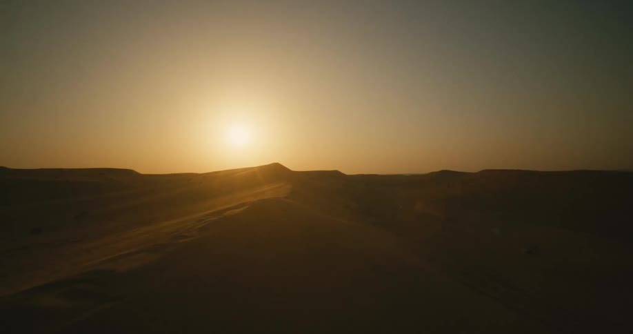 The sun setting over a sandy desert landscape in nature