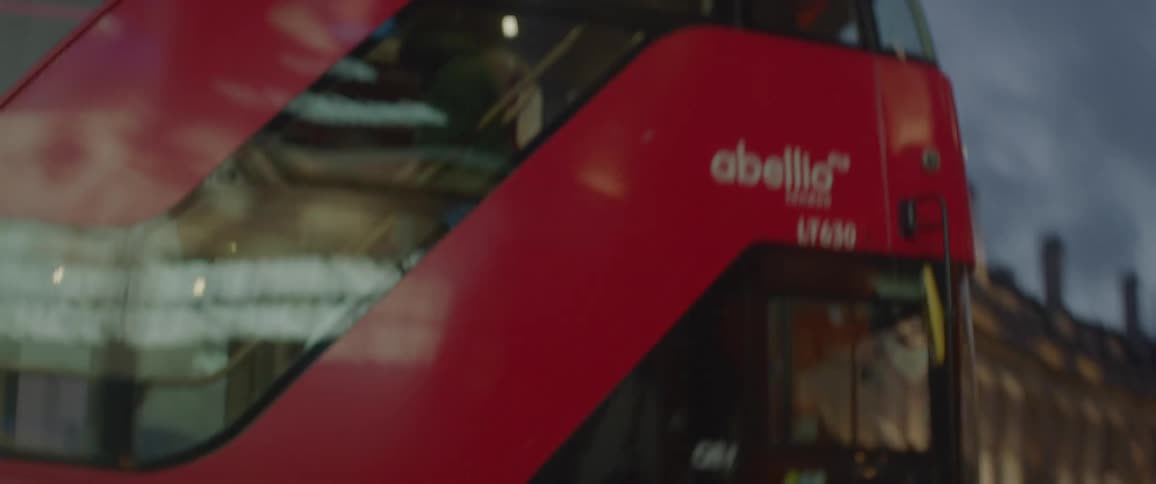 A double decker bus moves through a winding street