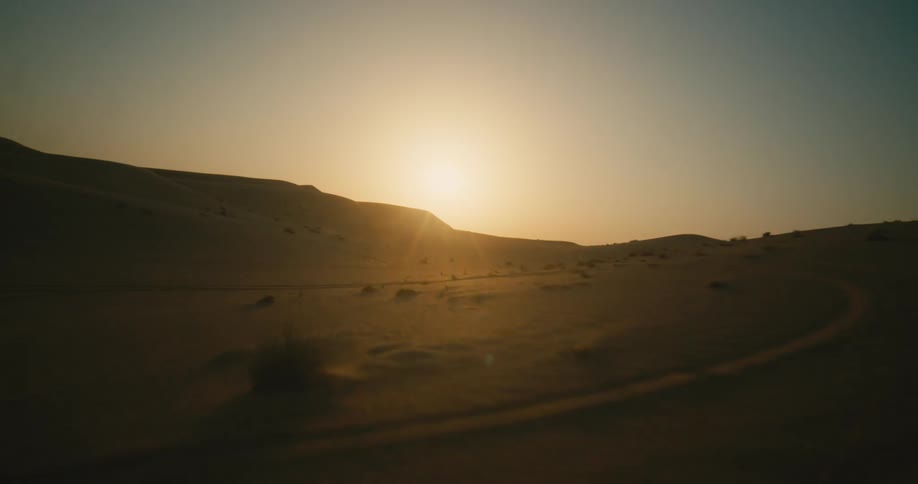 An aerial view of sandy dunes in a desert at sunset