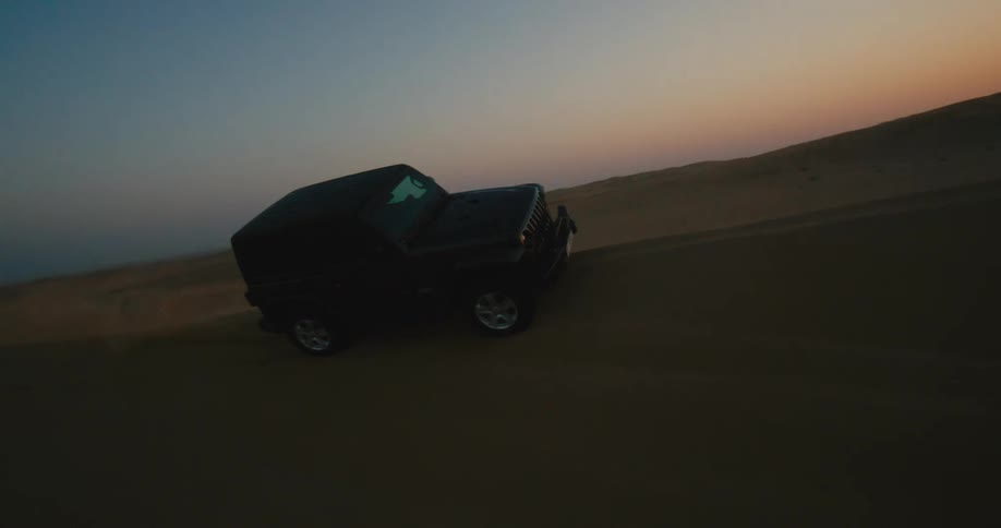A vehicle drives up the sand dunes