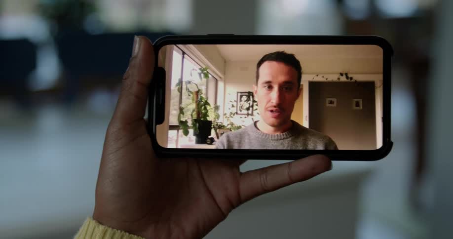 A person in a room on a smart phone with a wall and doorway in the background