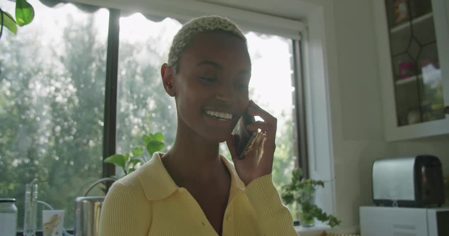 A woman is talking on her cell phone at home