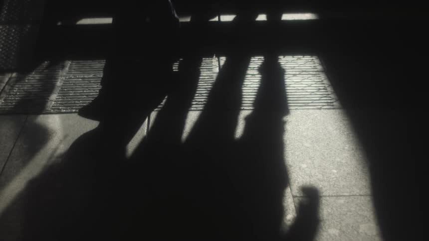 Shadows of people walking are on the ground