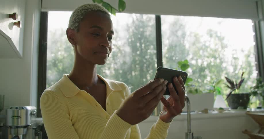 A woman smiles and waves to a cellphone