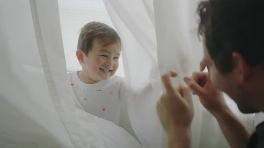 A man threatens to tickle his son next to a window