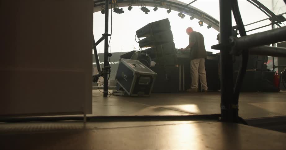 Two musicians stand behind dj equipment on stage in an outdoor stadium