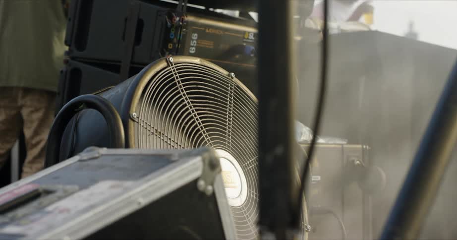 People are walking around equipment on a stage in a stadium
