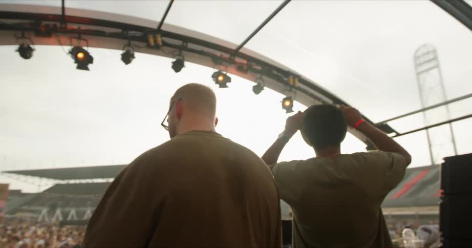 A dj sings along and dances on stage during a concert