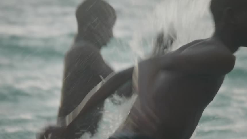 Two boys laugh as they splash each other in the ocean